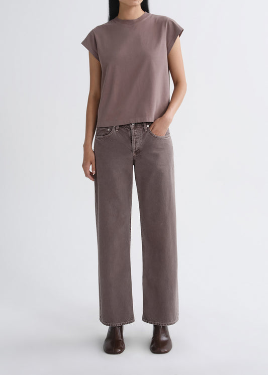 A model wearing a muted mauve-brown short-sleeve t-shirt and matching wide-leg jeans, paired with dark brown boots, against a grey background.