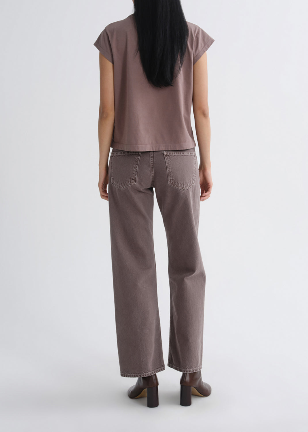 A model shown from the back wearing a mauve-brown short-sleeve top and matching wide-leg jeans, paired with brown block-heel boots, against a grey background.