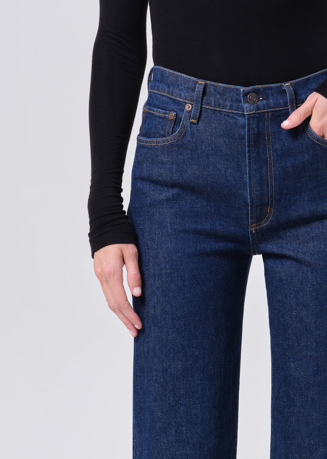 Person wearing blue jeans on a light gray background