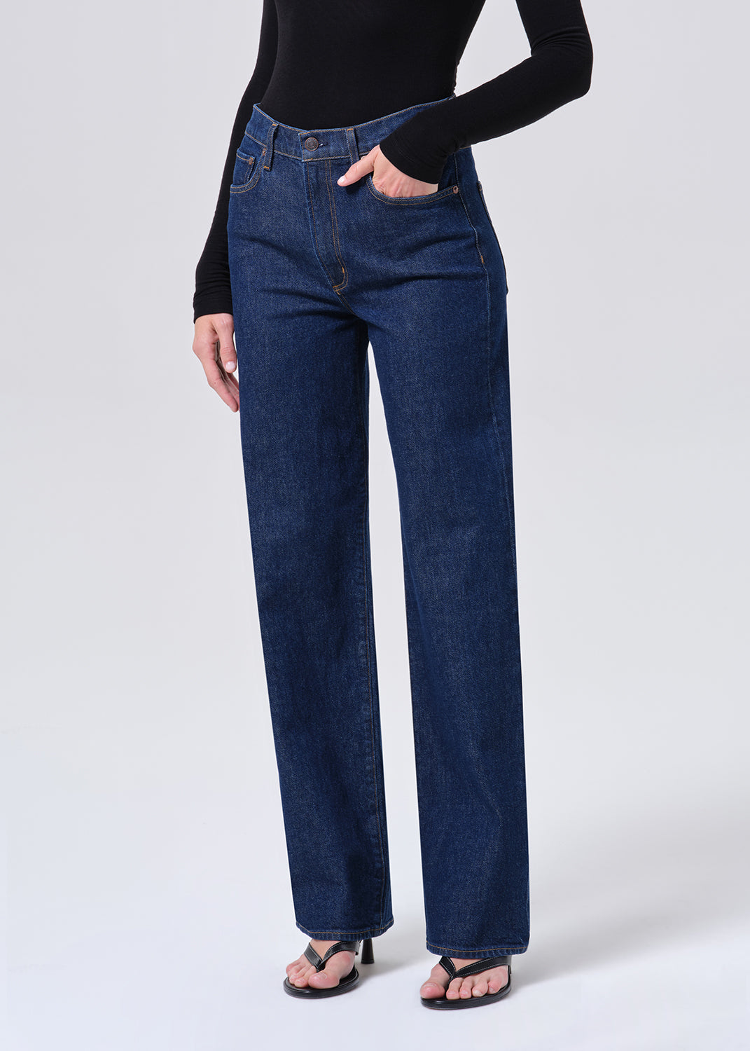 Person wearing blue jeans and a black top on a white background