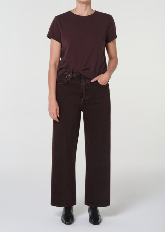 Person wearing a brown t-shirt and black jeans on a white background