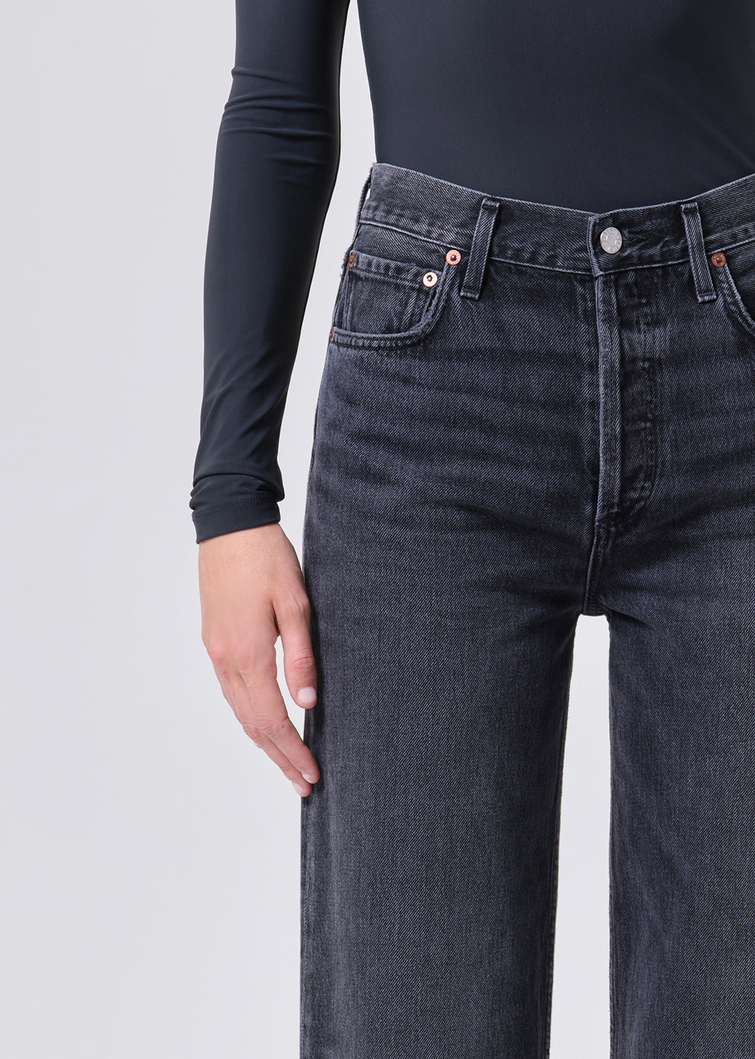 Person wearing dark gray jeans on a light gray background