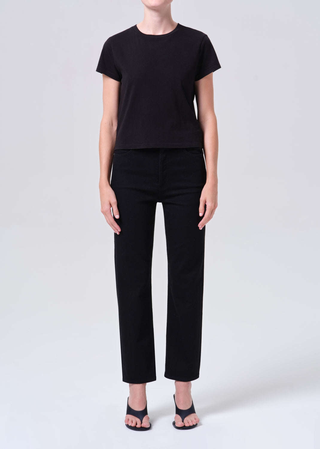 Person wearing a black t-shirt and black pants on a white background