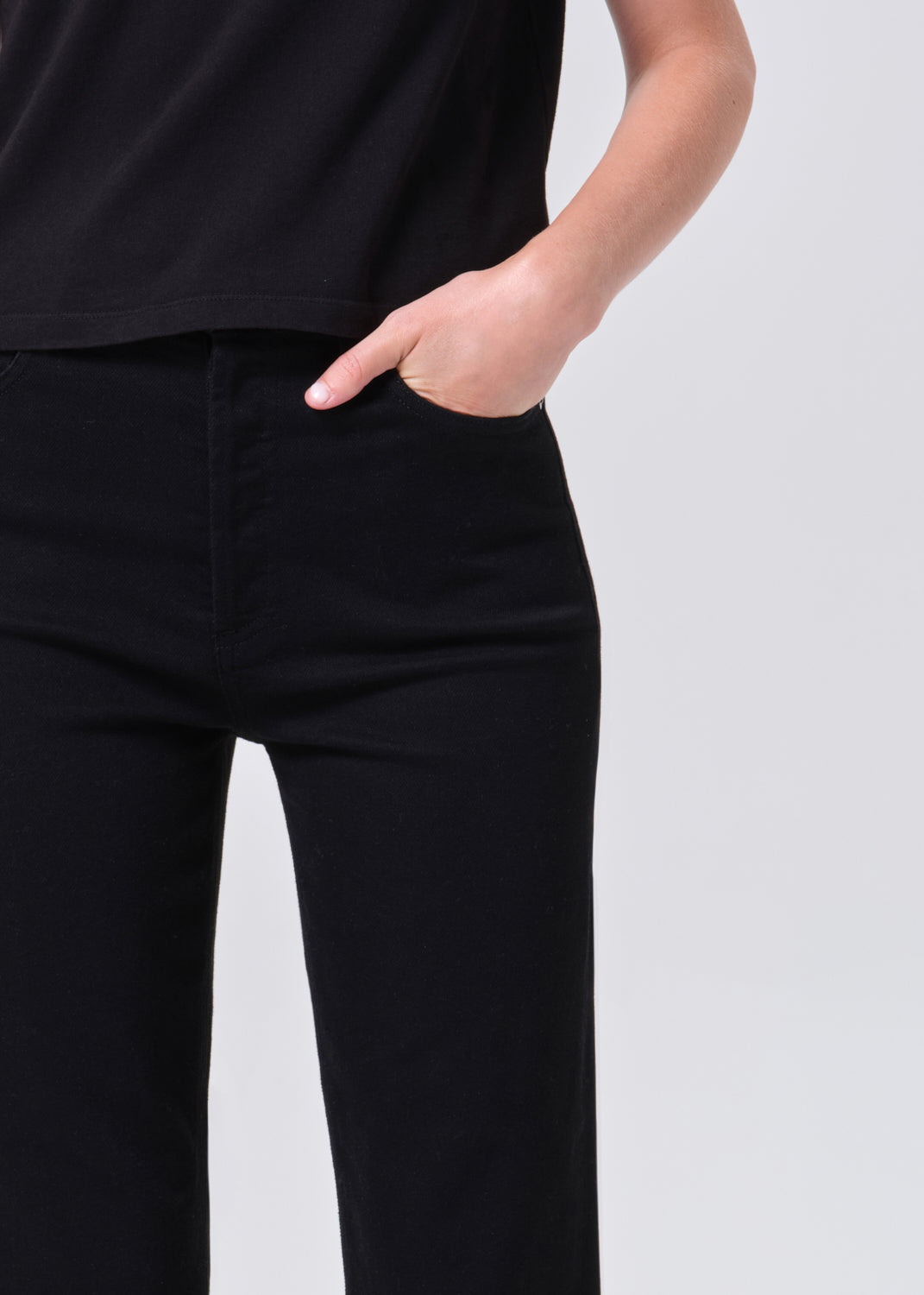 Person wearing black pants with a plain background