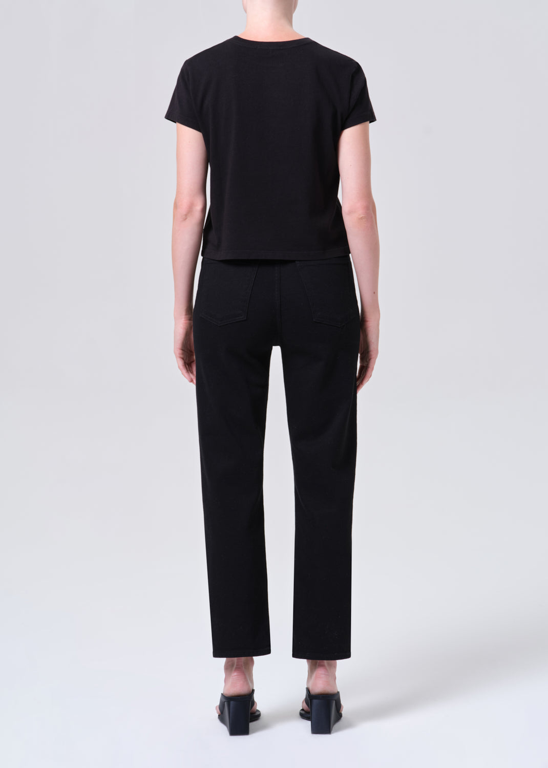 Person wearing a black t-shirt and black pants on a white background