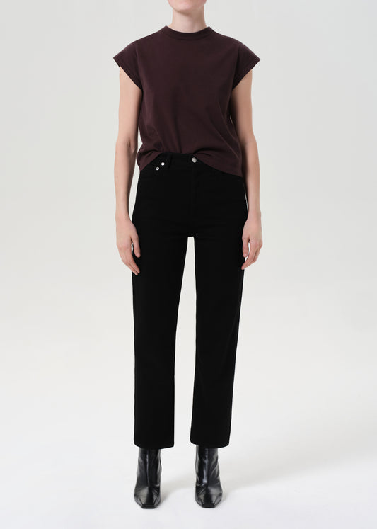 Person wearing a dark brown top and black pants on a white background