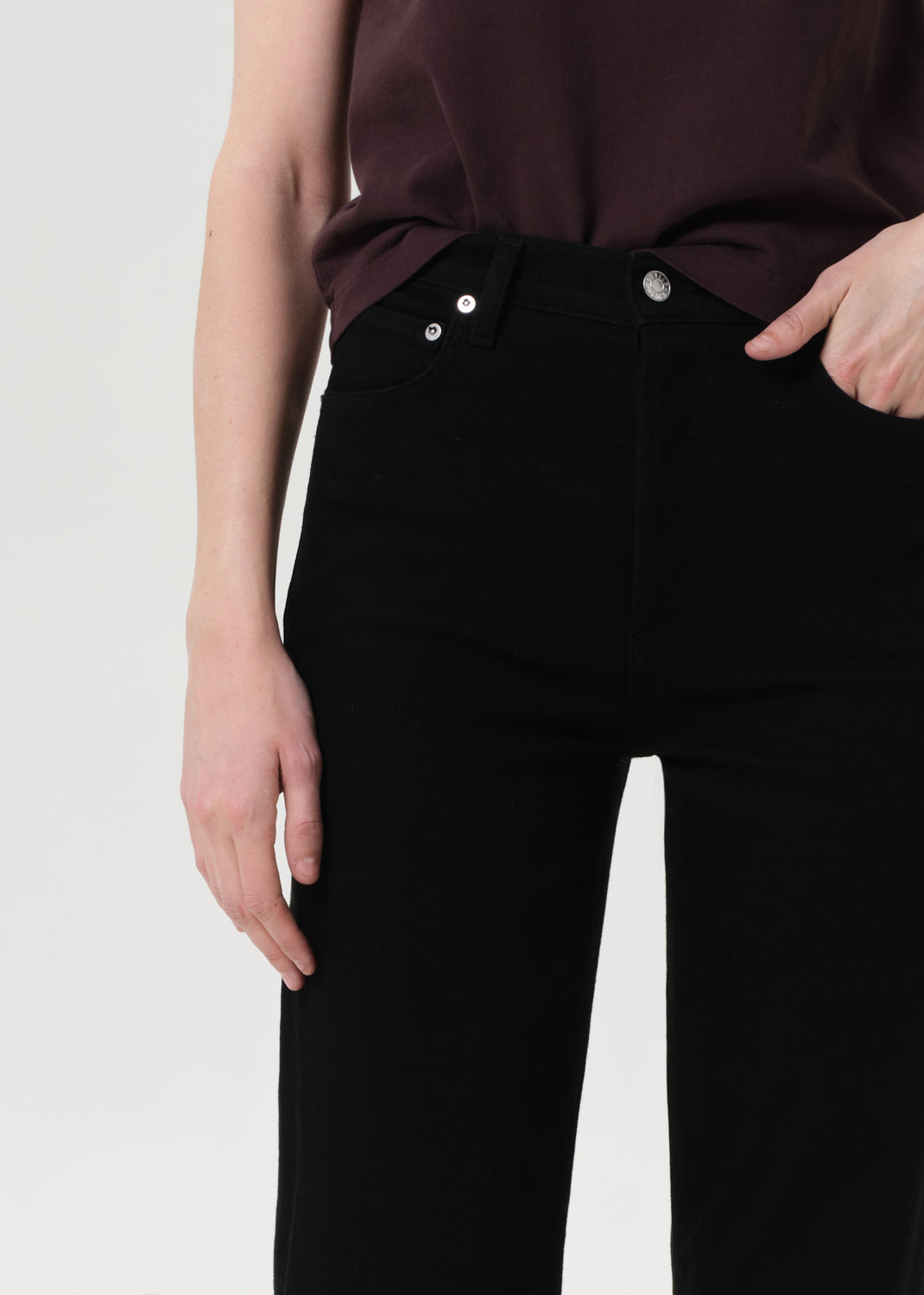 Person wearing a burgundy top and black pants on a light gray background