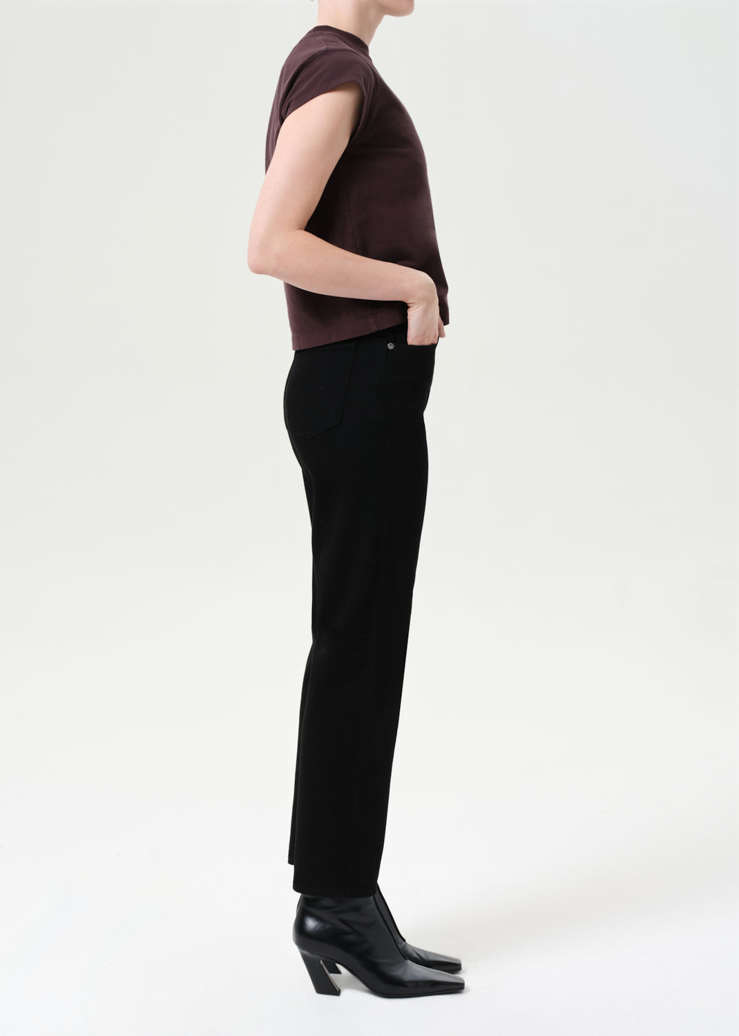 Person wearing a brown top and black pants on a white background