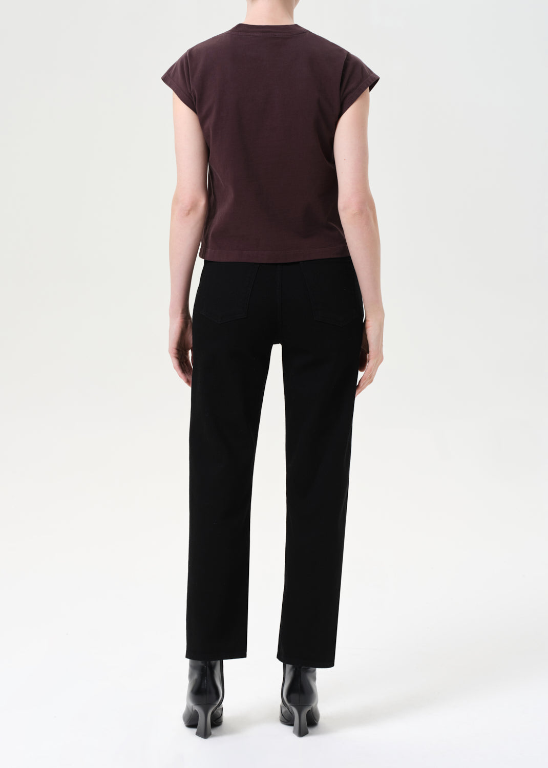 Person wearing a brown top and black pants on a white background
