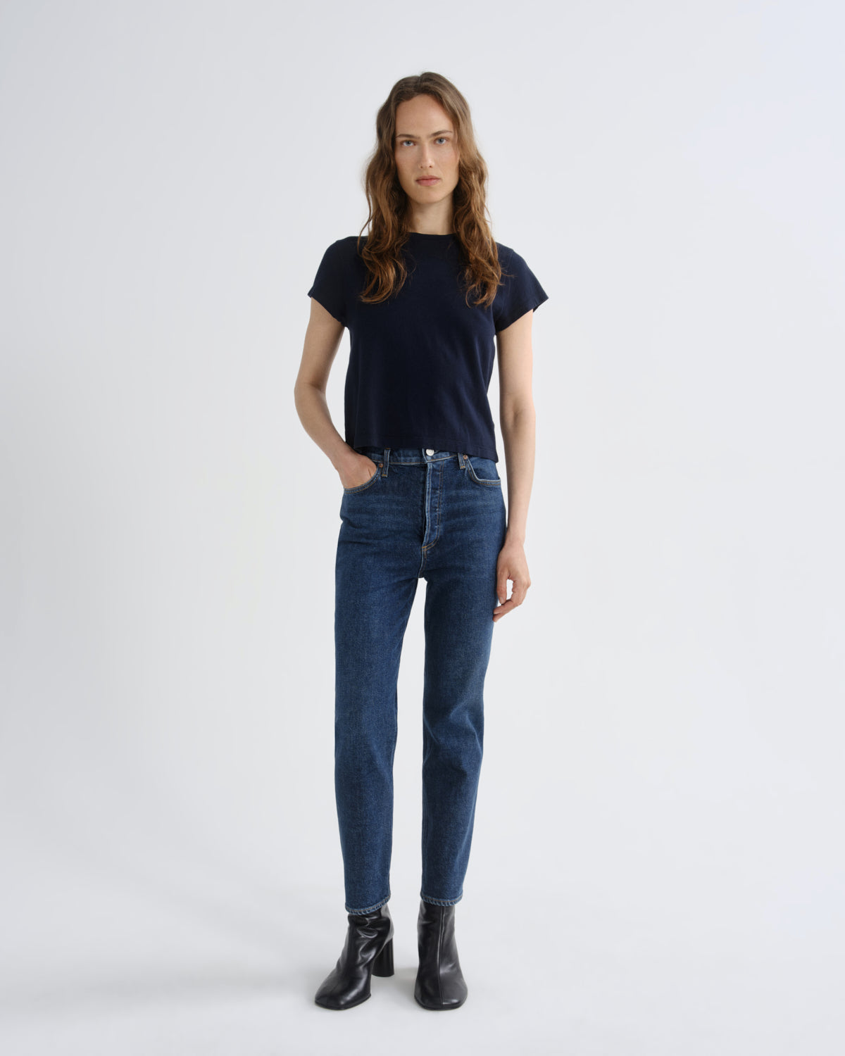 Woman wearing a black t-shirt and blue jeans on a white background
