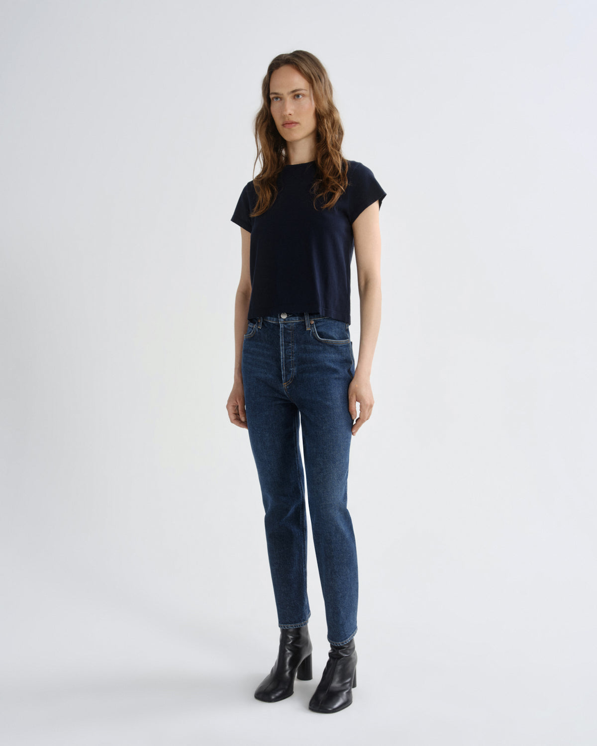 Woman wearing a black t-shirt and blue jeans on a white background