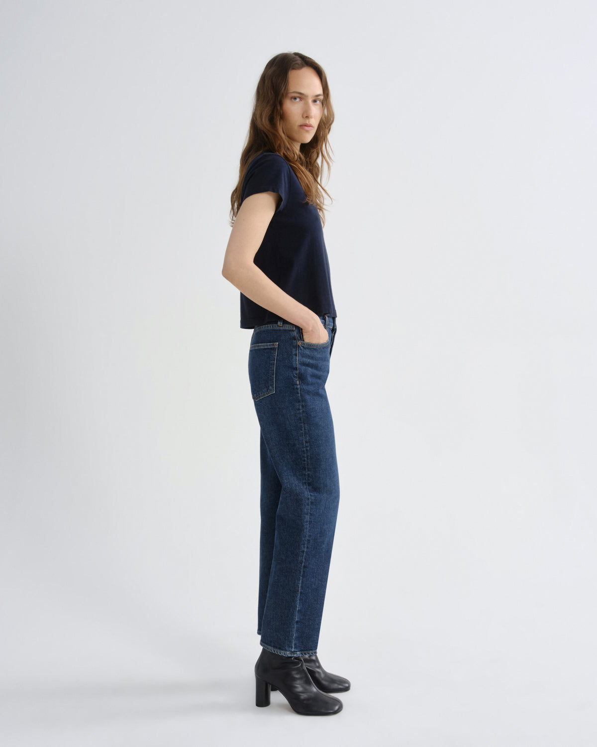 Woman wearing a dark blue t-shirt and jeans on a white background