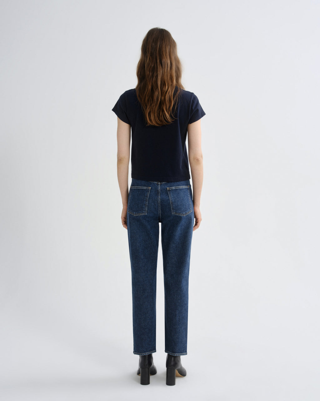 Person wearing a black t-shirt and blue jeans on a white background