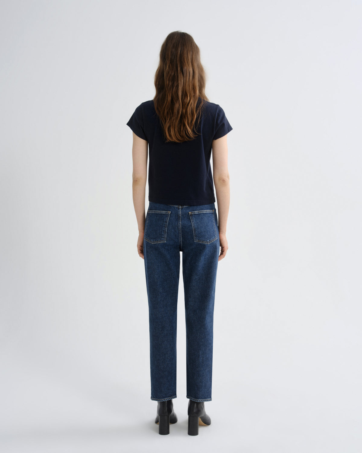 Person wearing a black t-shirt and blue jeans on a white background