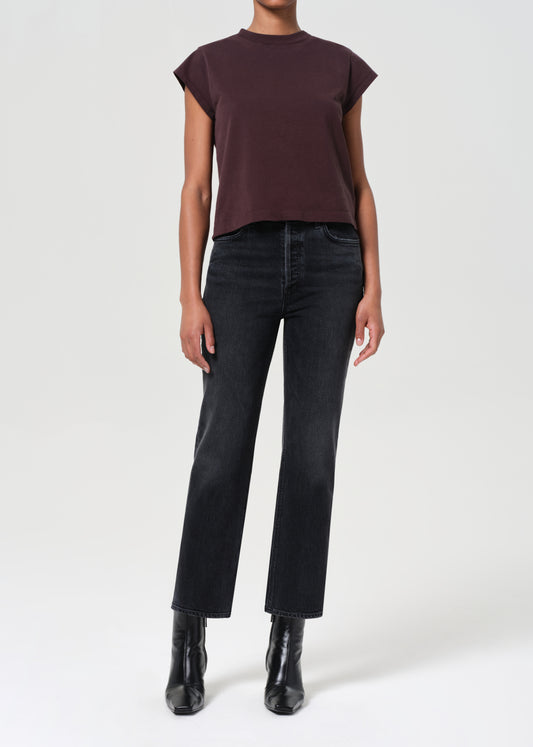 Person wearing a brown top and black jeans on a white background