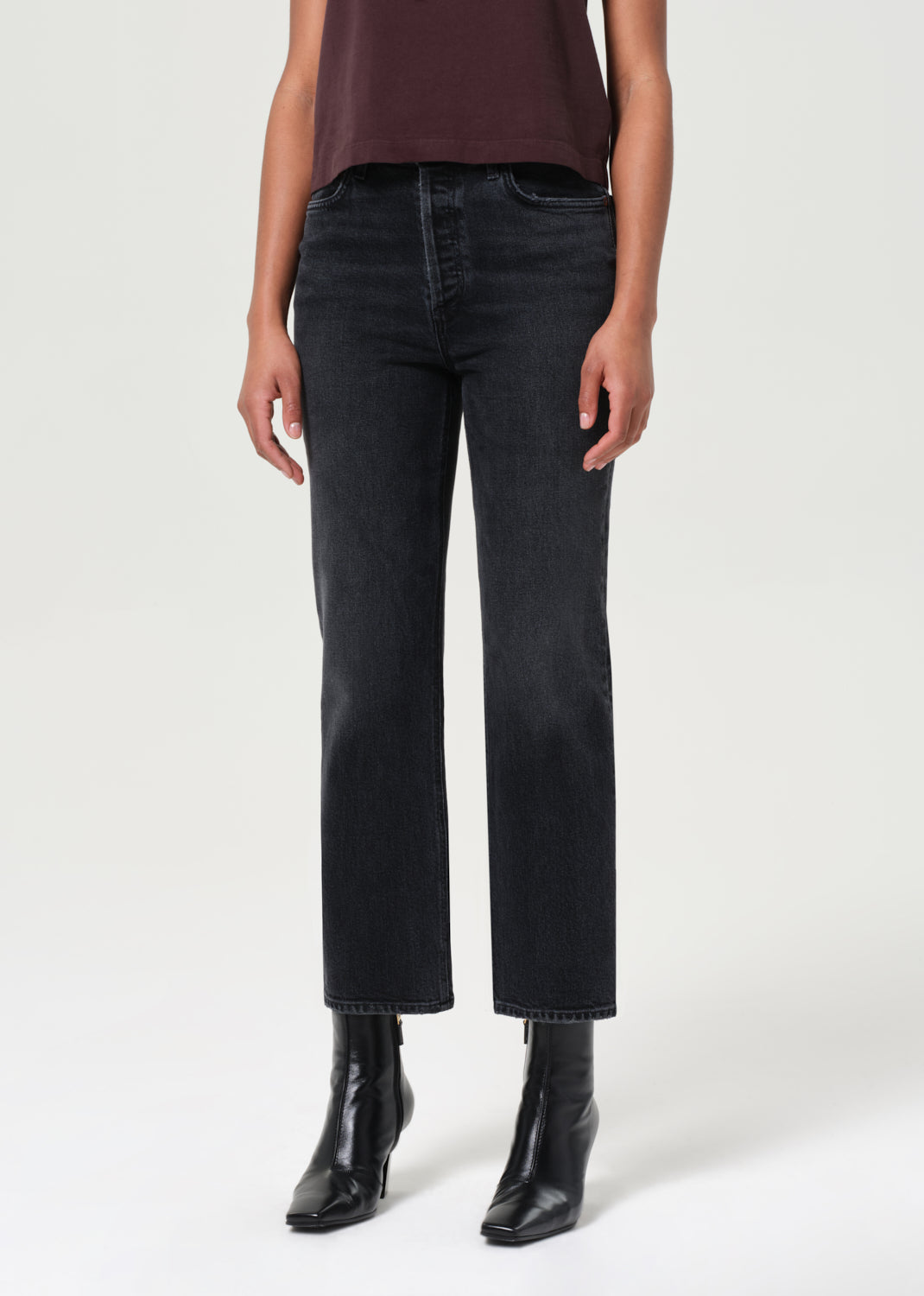 Person wearing black jeans and black boots on a white background