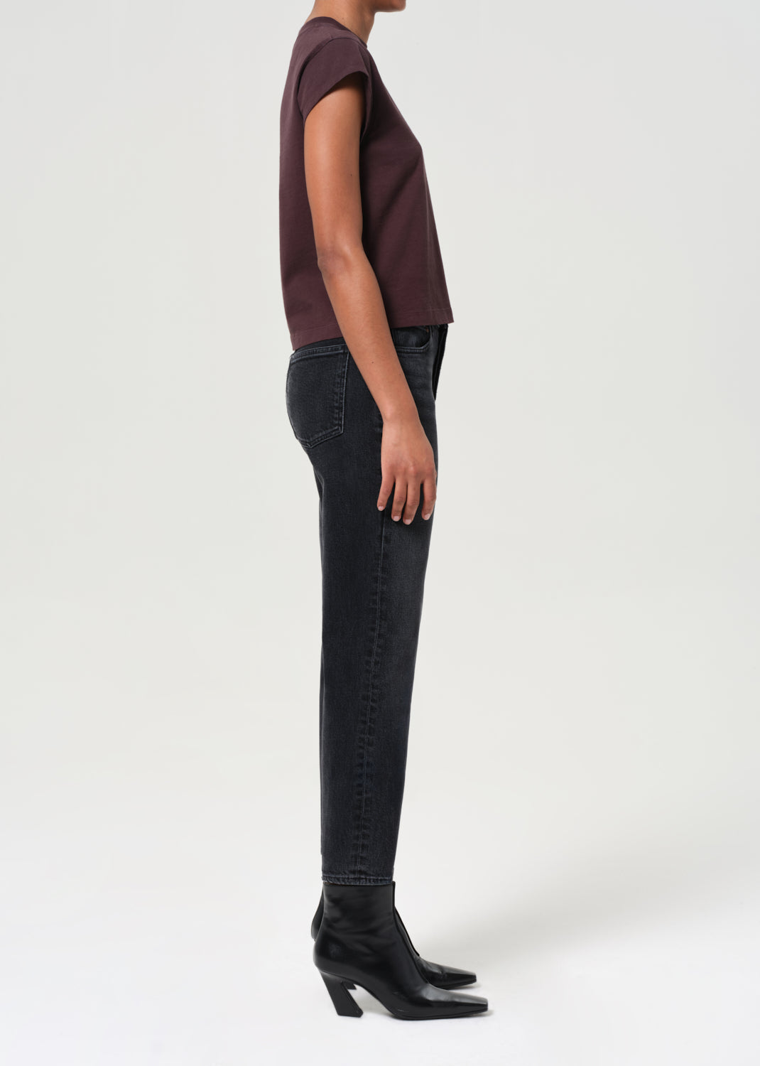 Person wearing a maroon top and black jeans on a white background