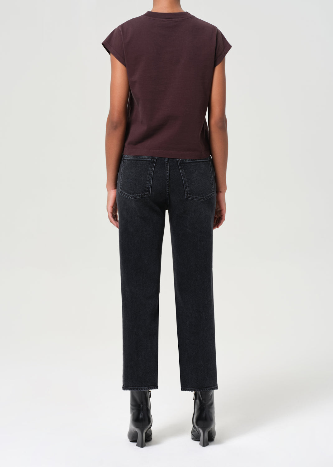 Person wearing a brown top and black pants on a white background