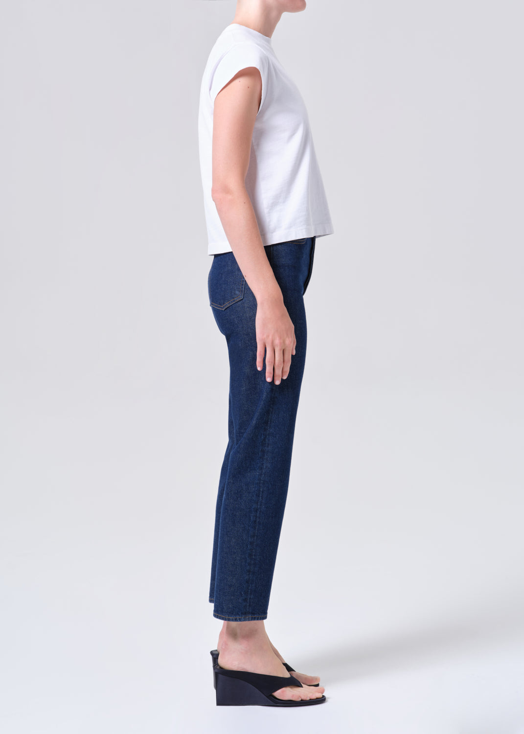 Person wearing a white top and blue jeans on a plain background