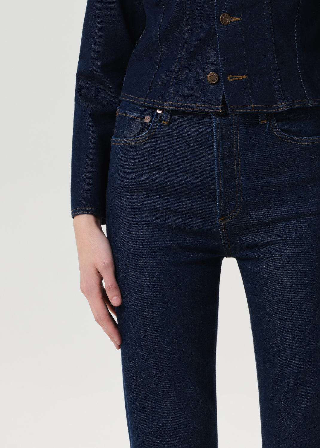 Person wearing dark blue denim jeans and a matching jacket on a light gray background