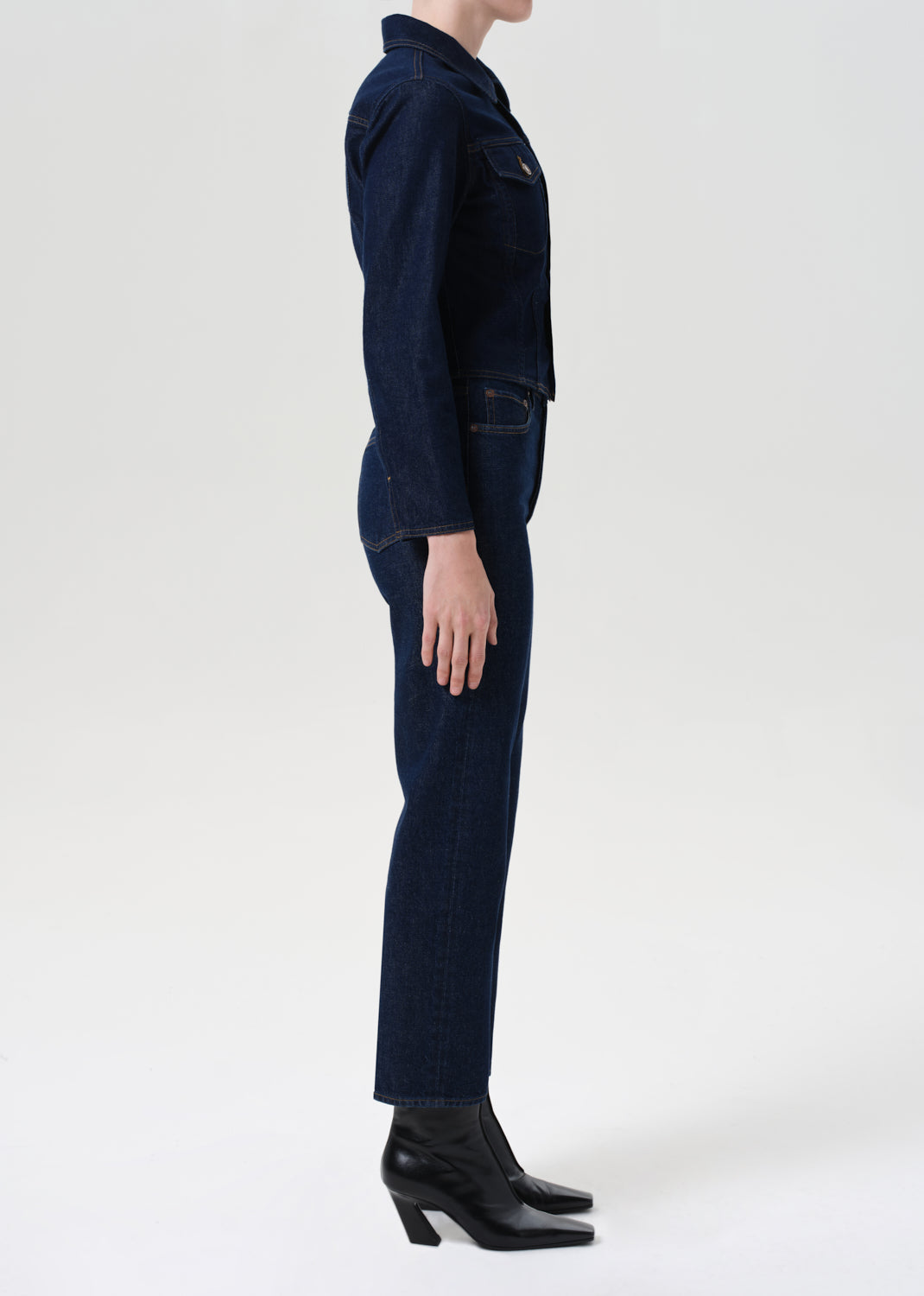 Person wearing a dark blue denim outfit on a white background
