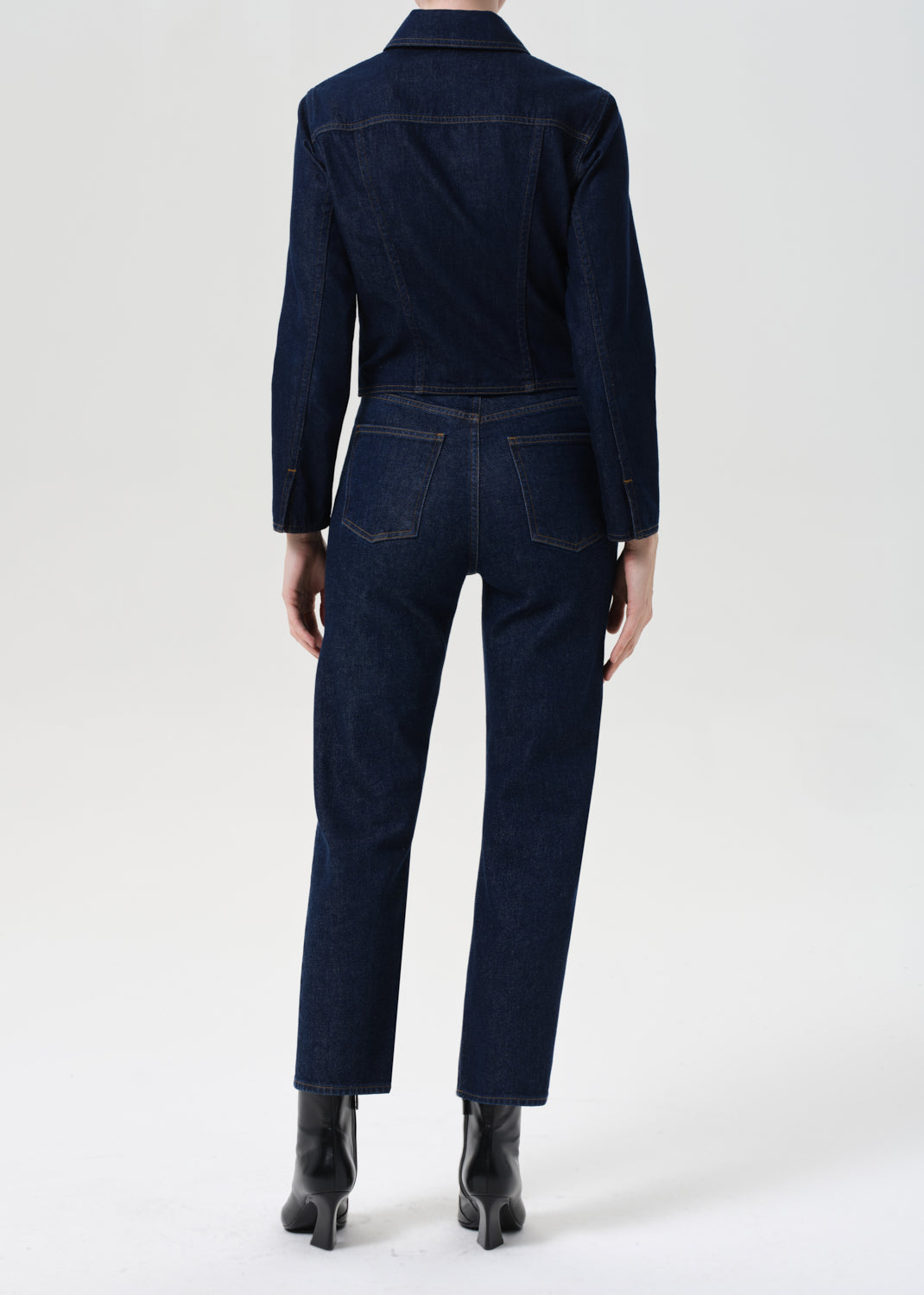 Person wearing a dark denim outfit on a white background