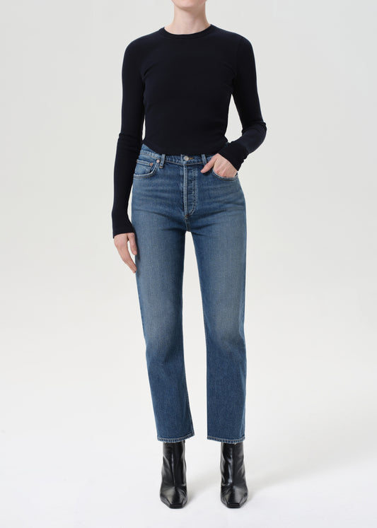 Person wearing a black sweater and blue jeans on a white background