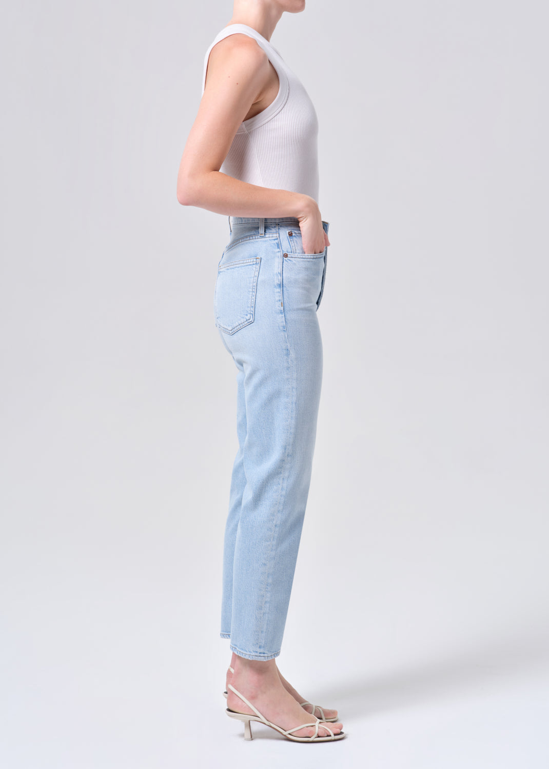 Person wearing light blue jeans and a white top on a plain background