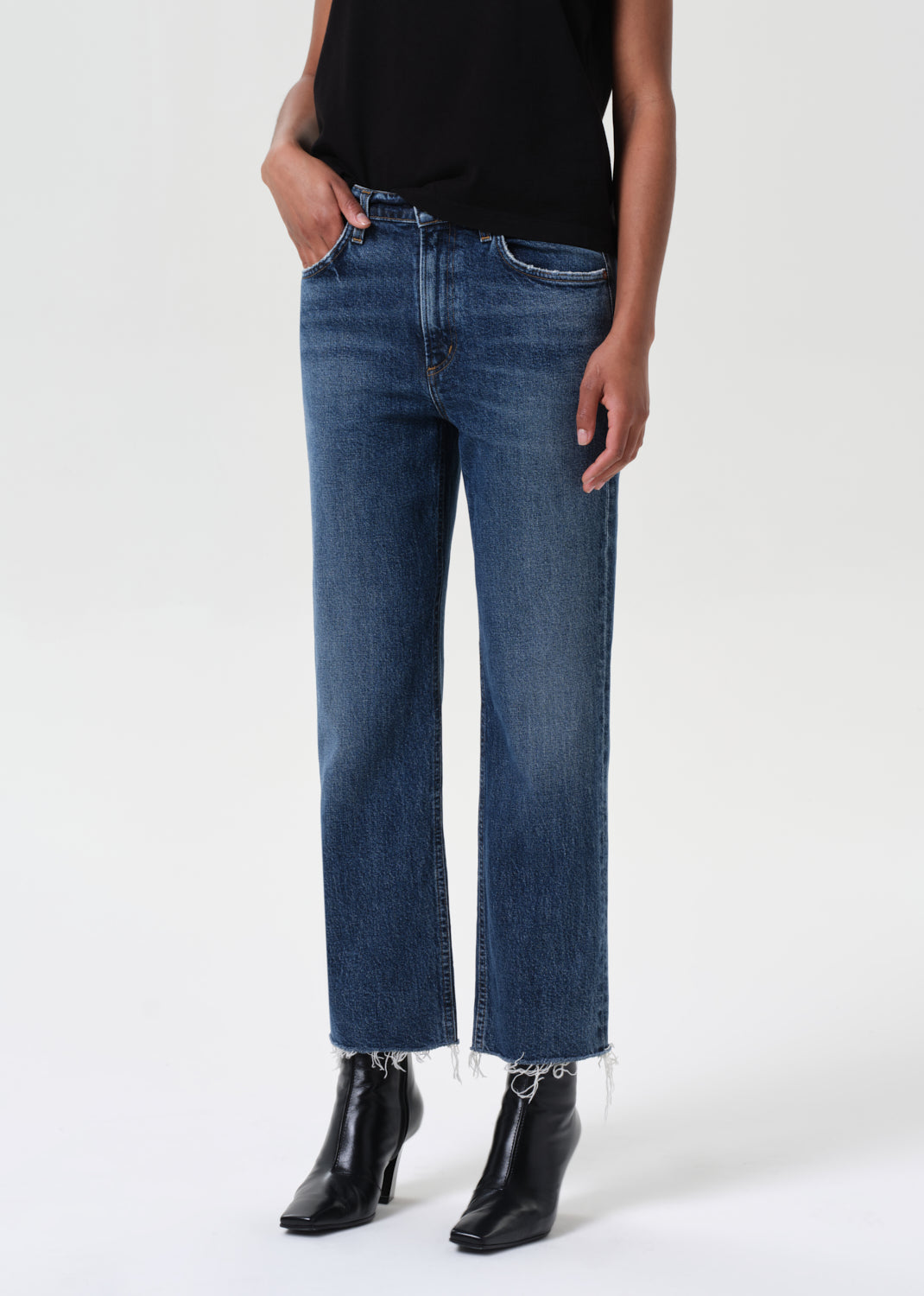 Person wearing blue jeans and black boots on a white background