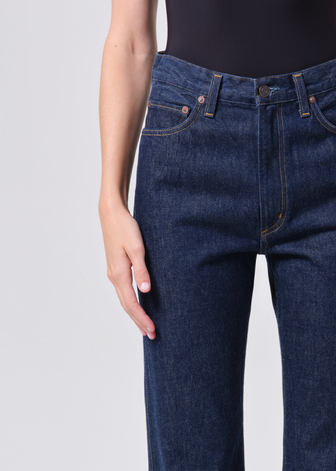 Dark blue jeans worn by a person on a light gray background