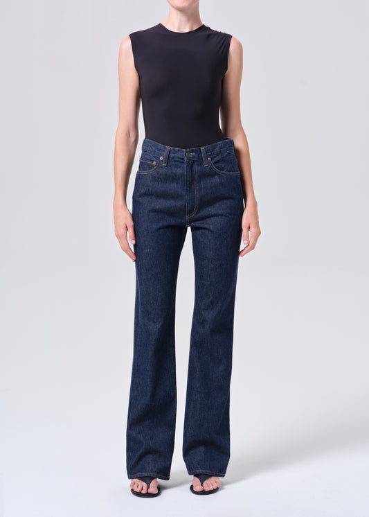 Person wearing dark blue jeans and a black sleeveless top on a white background