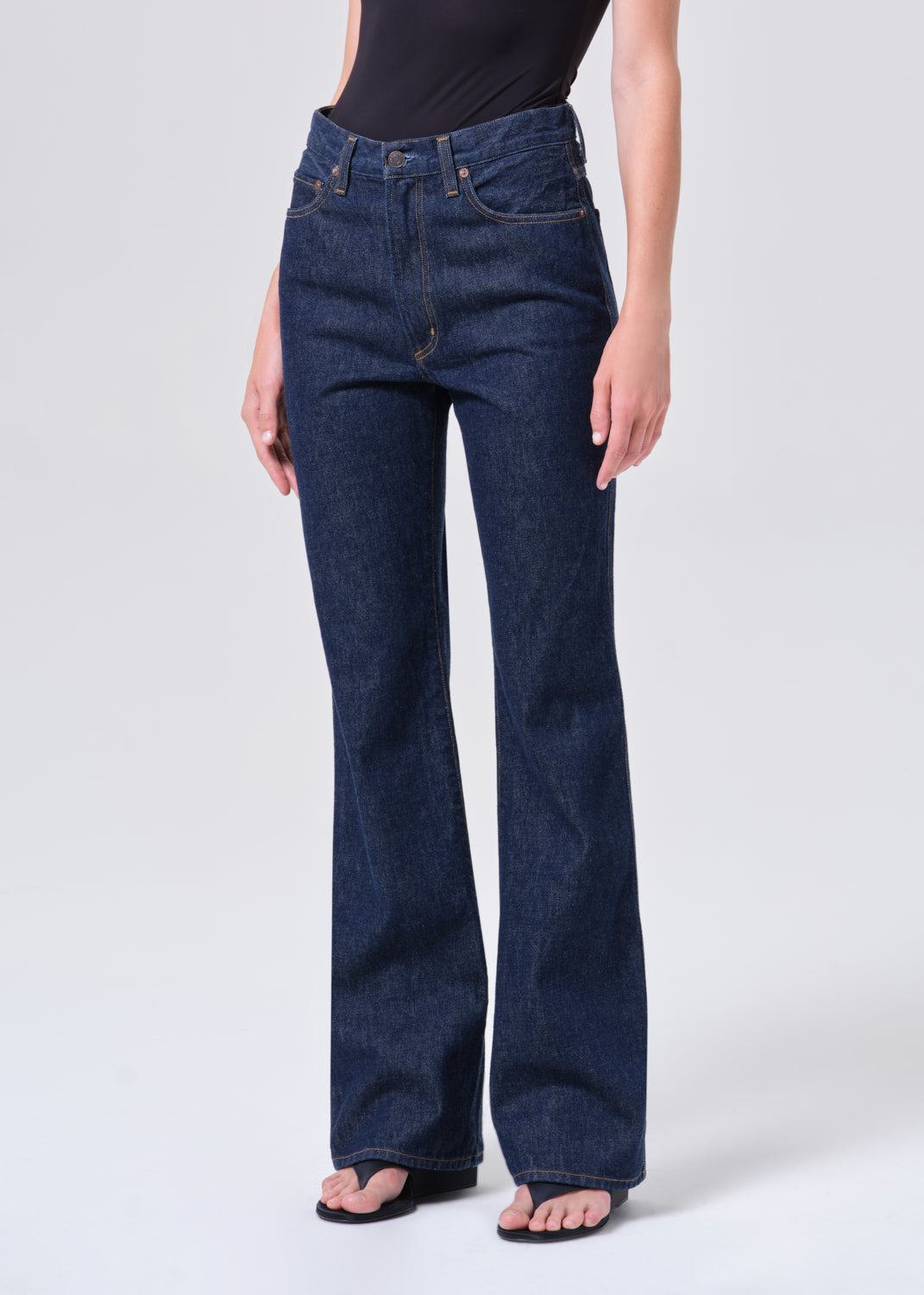 Person wearing dark blue flared jeans on a white background