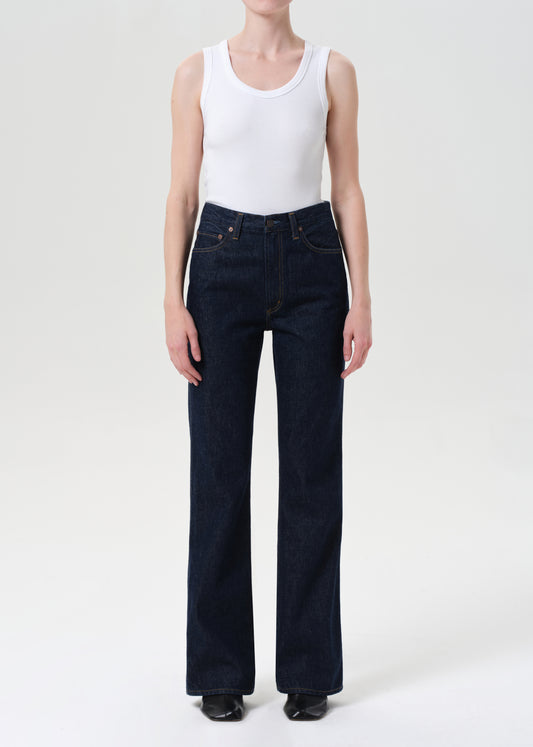 Person wearing a white tank top and dark blue jeans on a white background