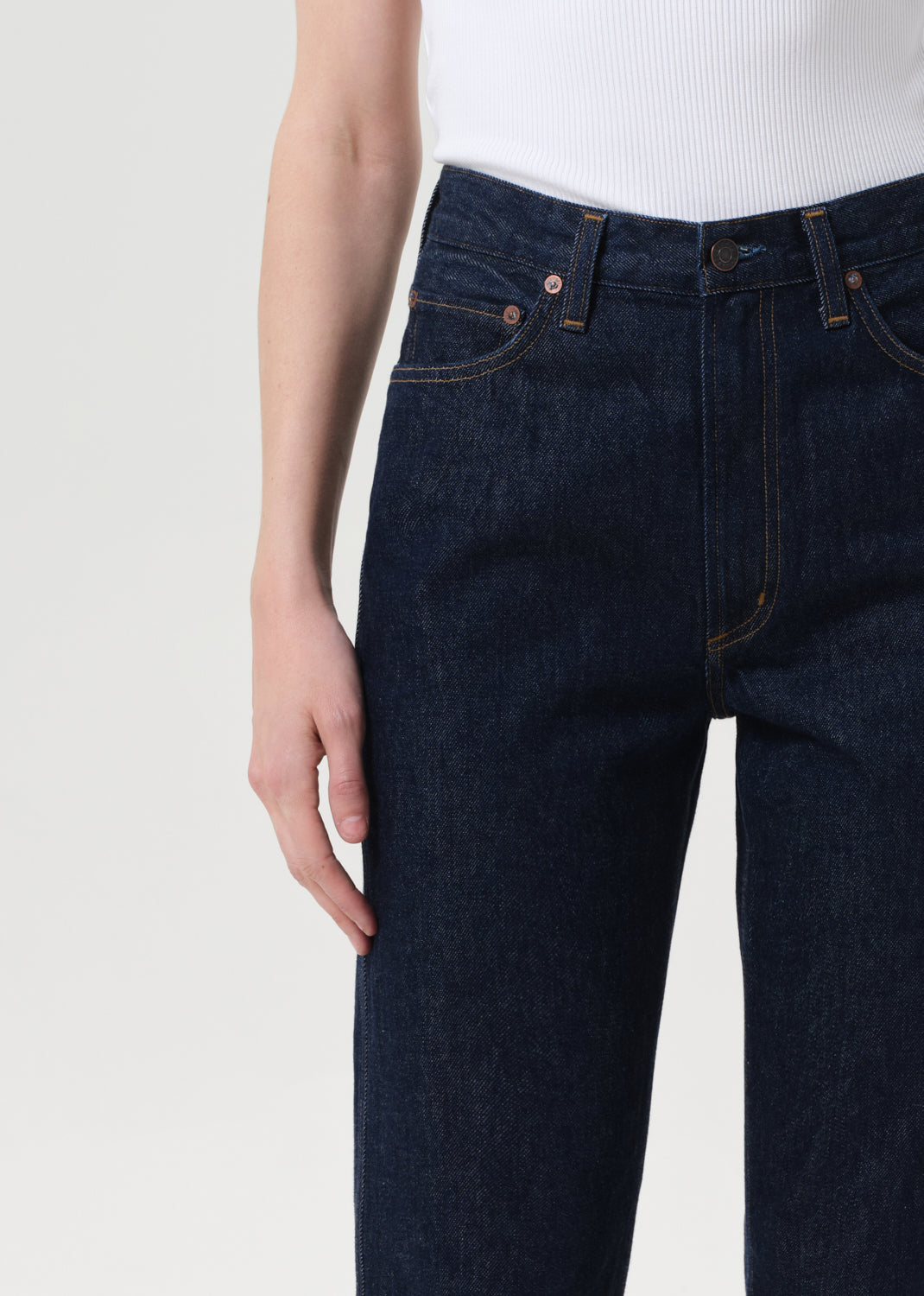 Dark blue jeans worn by a person on a white background