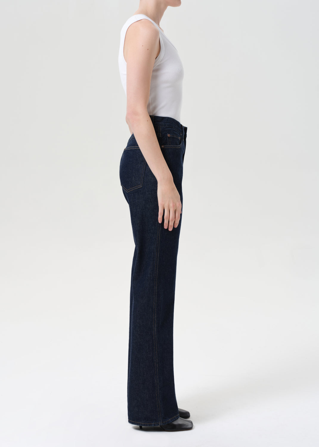 Person wearing dark blue jeans and a white top on a white background