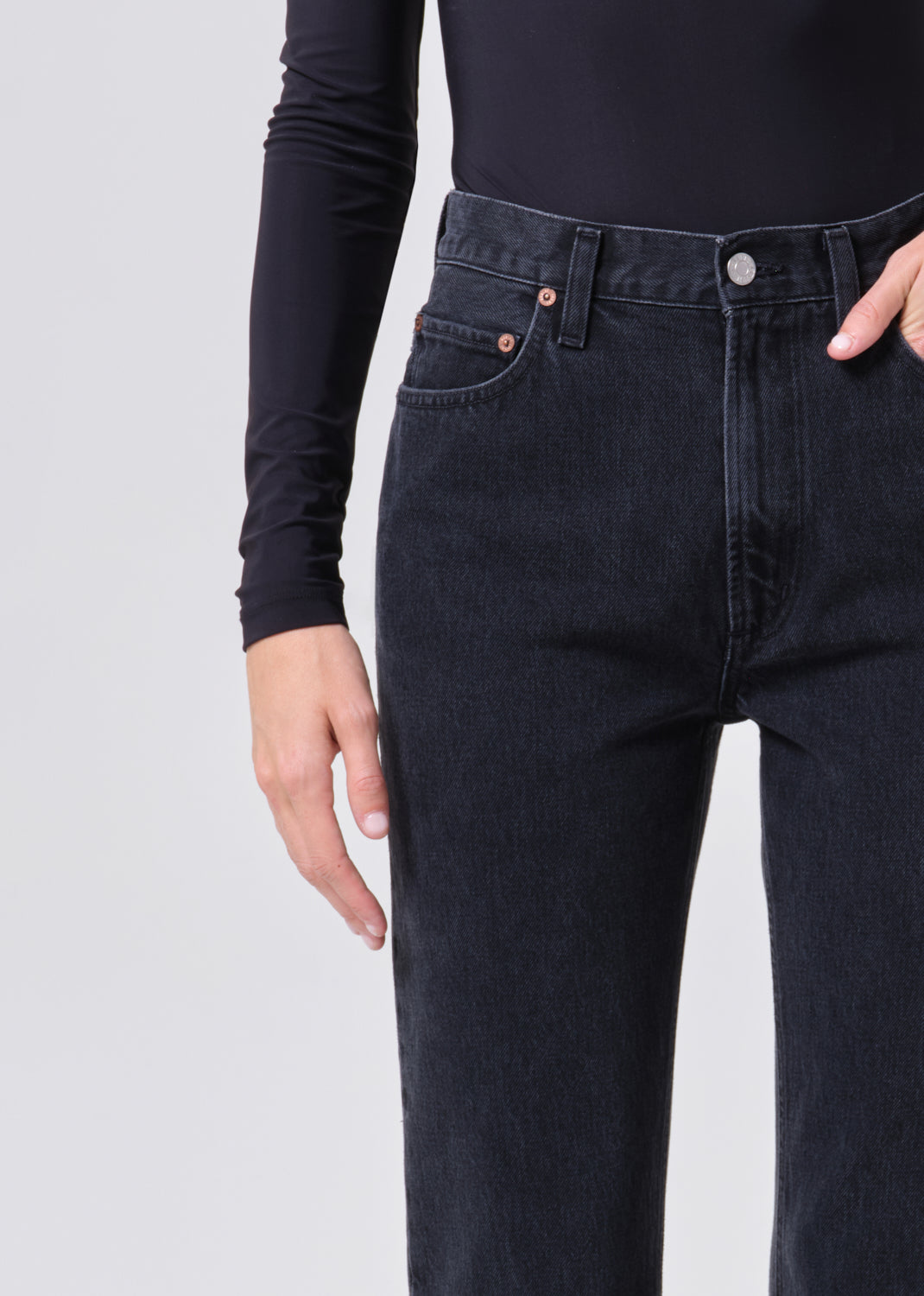 Person wearing black jeans on a plain background