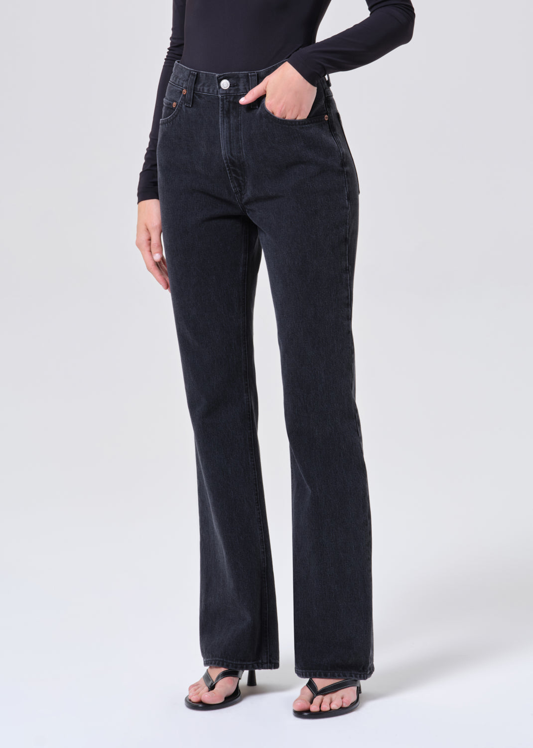 Person wearing black flared jeans on a white background