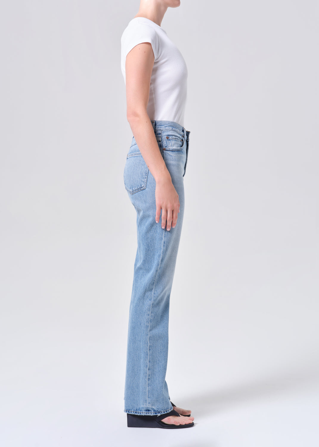 Person wearing light blue jeans and a white t-shirt on a plain background