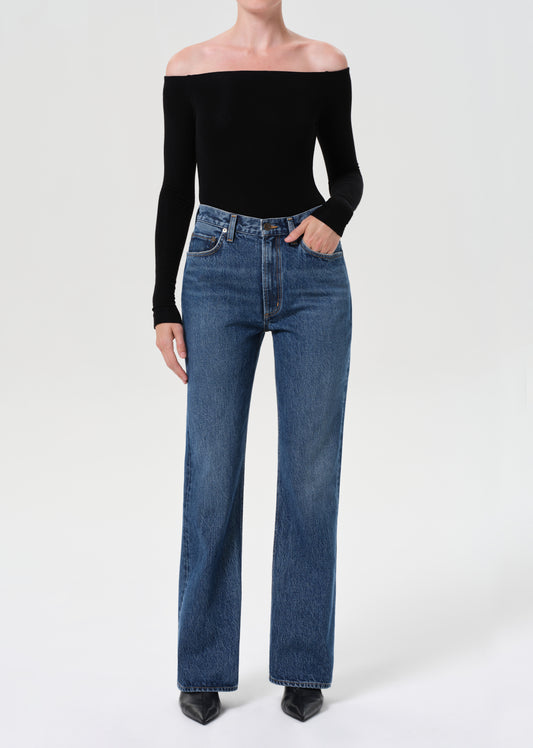 Person wearing a black off-shoulder top and blue jeans on a white background