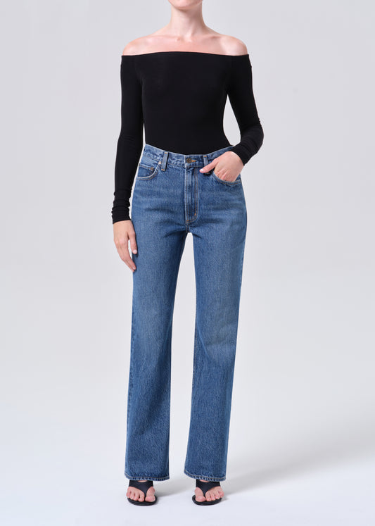 Person wearing a black off-shoulder top and blue jeans on a white background