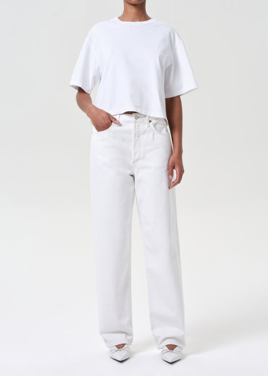 Person wearing a white t-shirt and white jeans on a plain background