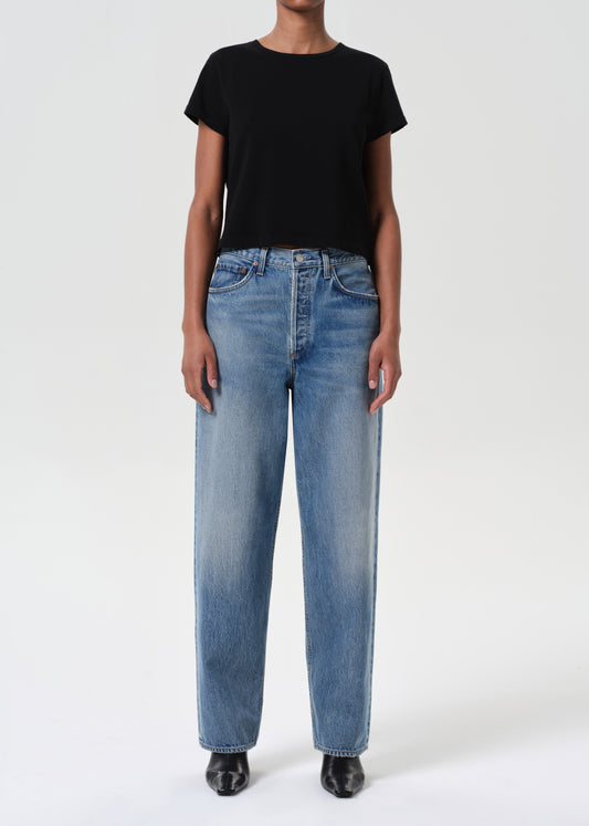 Person wearing blue jeans and a black t-shirt on a white background