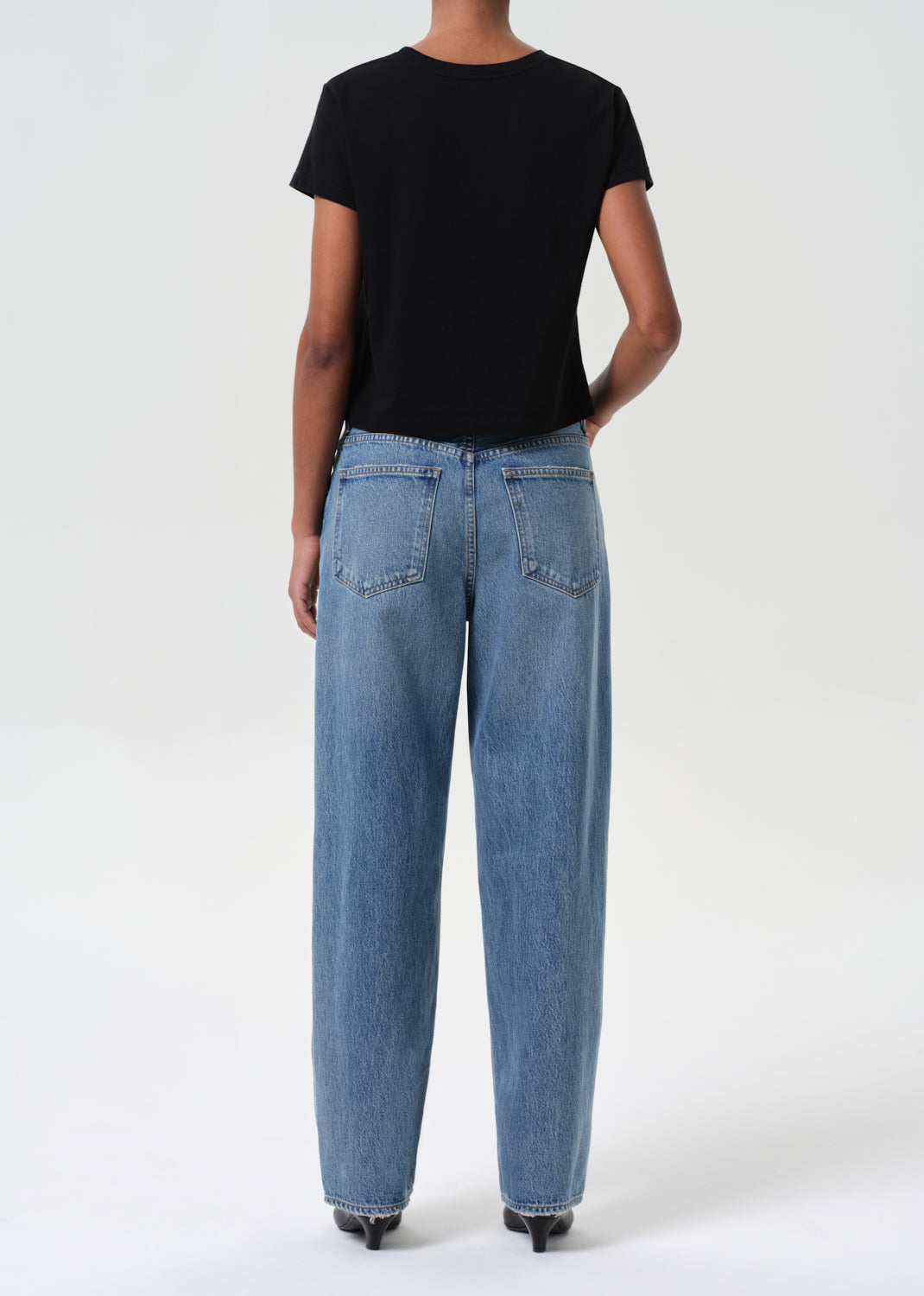 Person wearing blue jeans and a black t-shirt on a white background