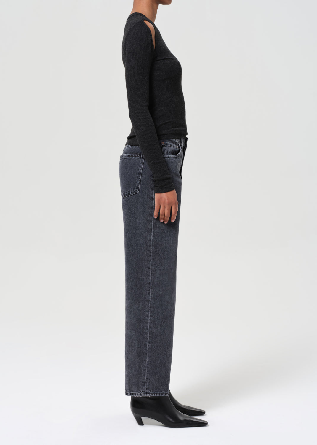 Person wearing a black long-sleeve top and dark blue jeans on a white background