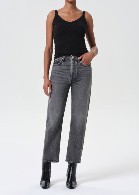 Person wearing a black tank top and gray jeans on a white background