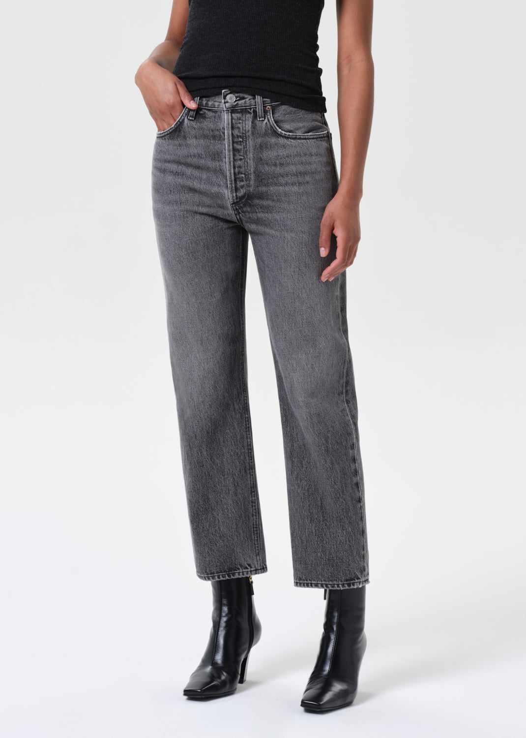 Person wearing gray jeans and black boots on a white background