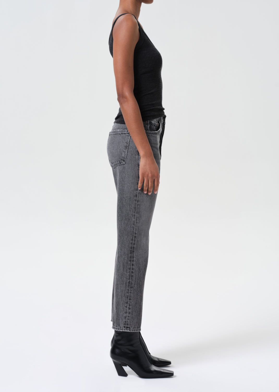 Person wearing gray jeans and black boots on a white background