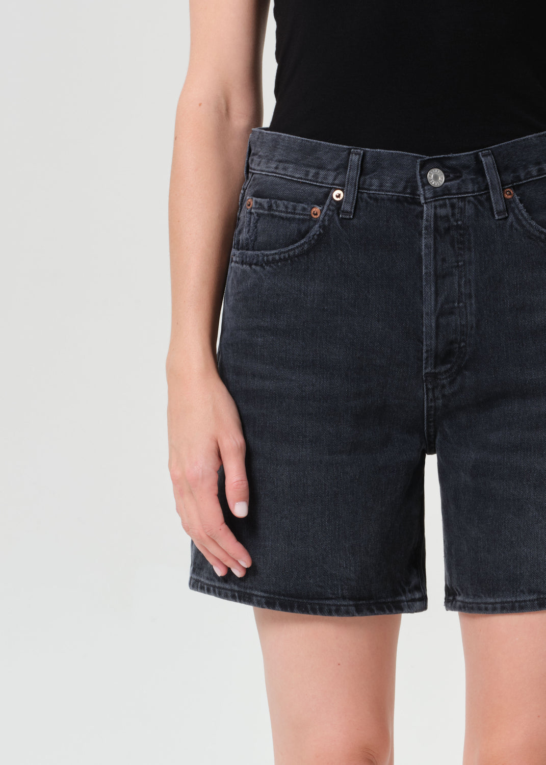 Black denim shorts worn by a person on a white background