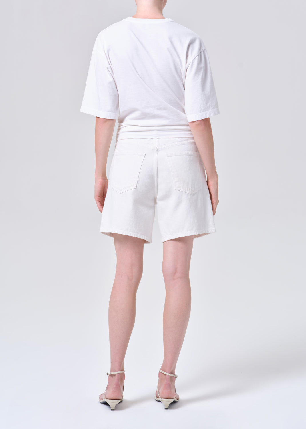 Person wearing a white t-shirt and shorts on a plain background