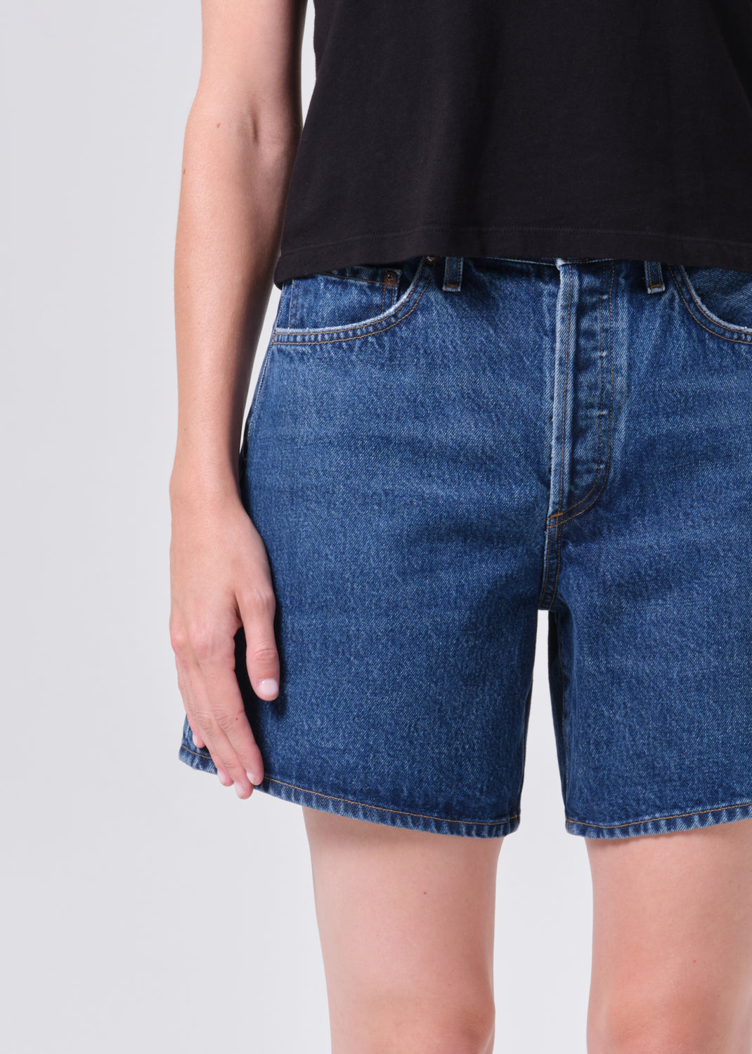 Person wearing blue denim shorts on a plain background